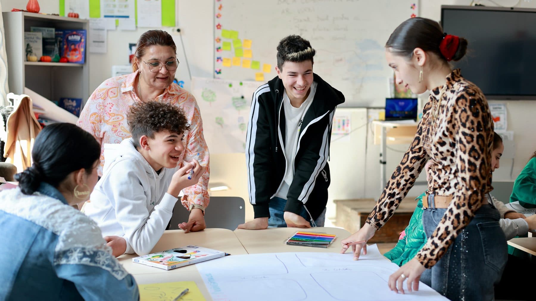 Elevi și profesoară colaborând în clasă